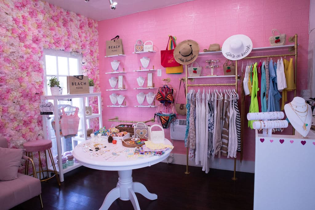 Racks of beachwear and swimsuits against the pink flower wall in the boutique