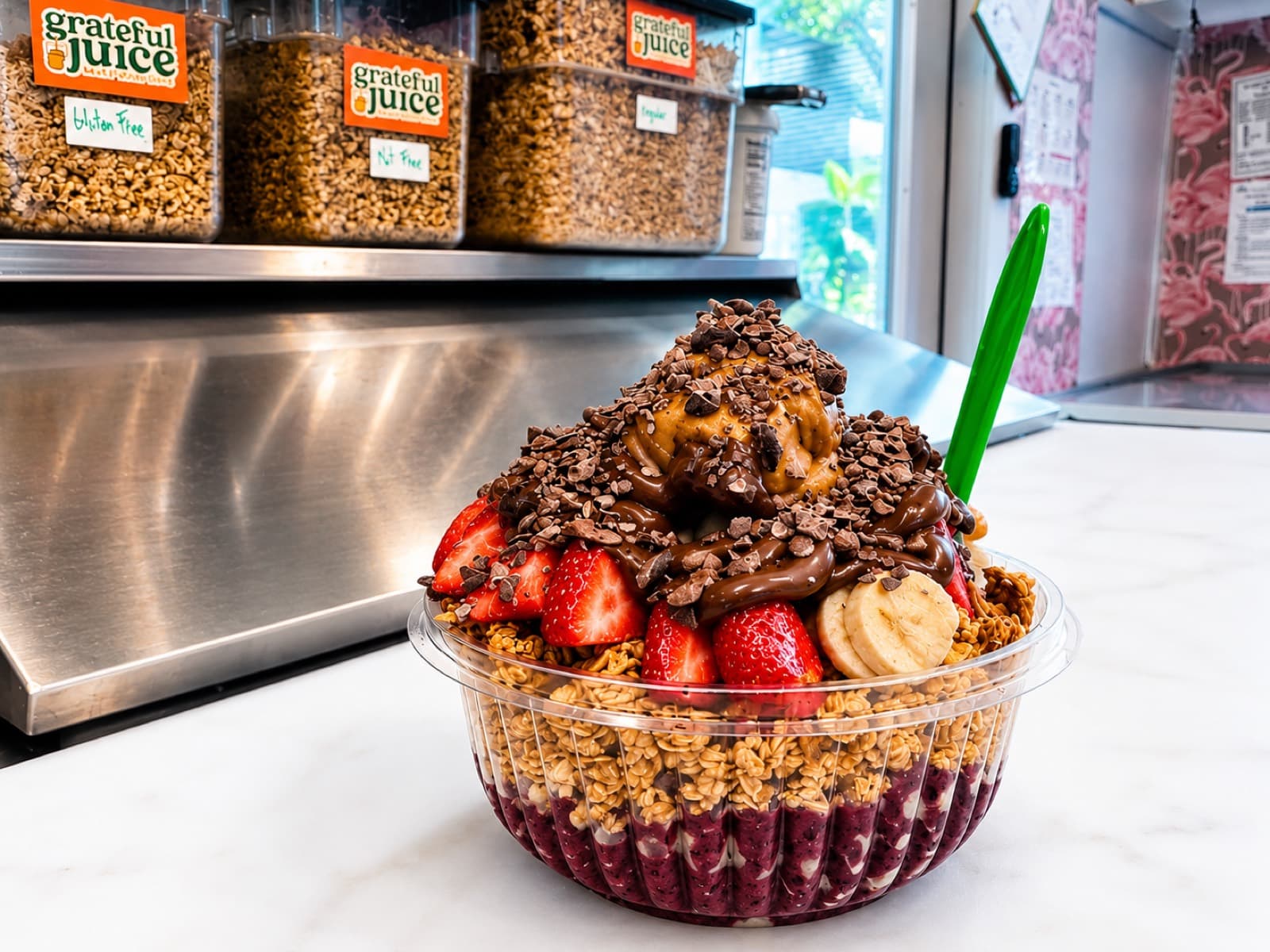 An açaí bowl piled with strawberries, banana, granola, peanut butter and chocolate on the Grateful Juice counter
