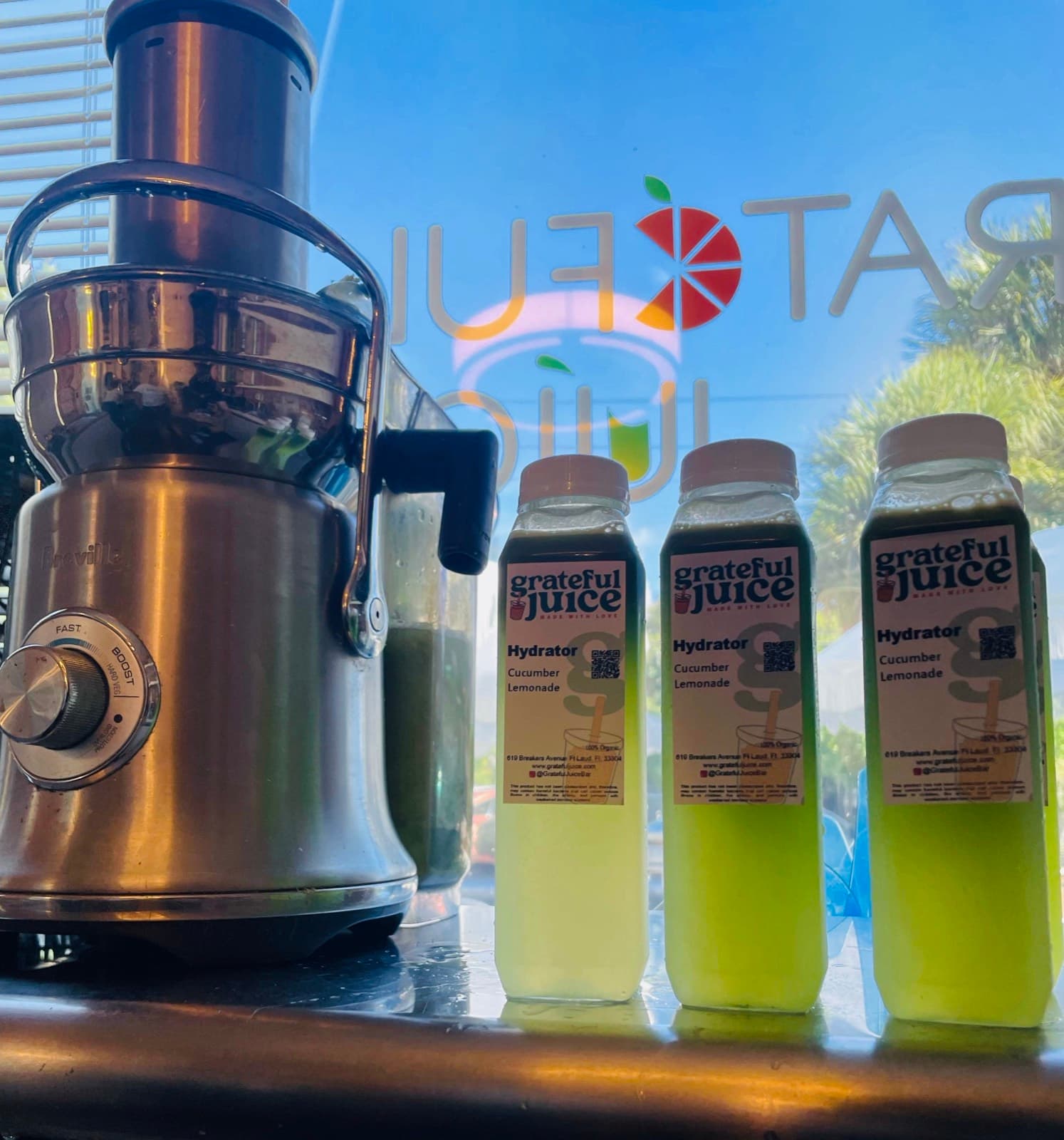 Bottles of cold-pressed Hydrator juice lined up beside the juicer in the shop window