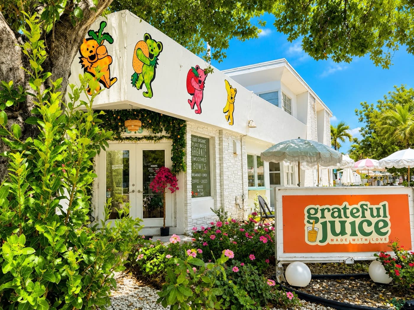 The Grateful Juice storefront in North Beach Village, with dancing-bear murals above the door