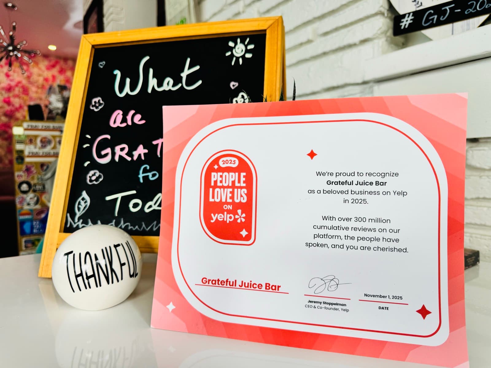 The 2025 People Love Us on Yelp certificate awarded to Grateful Juice Bar, displayed on the counter
